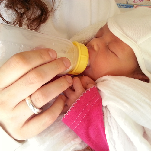 Mother feeding newborn baby with bottle